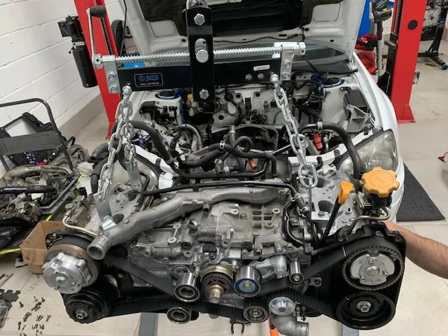 A man working on a car engine in a garage.