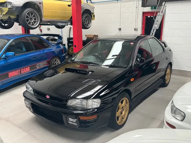 A car is parked in a garage with other cars.