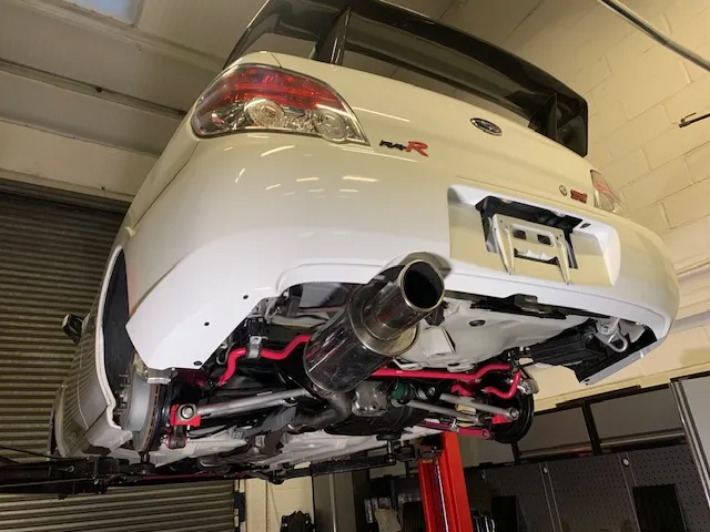 A white car is on a lift in a garage.